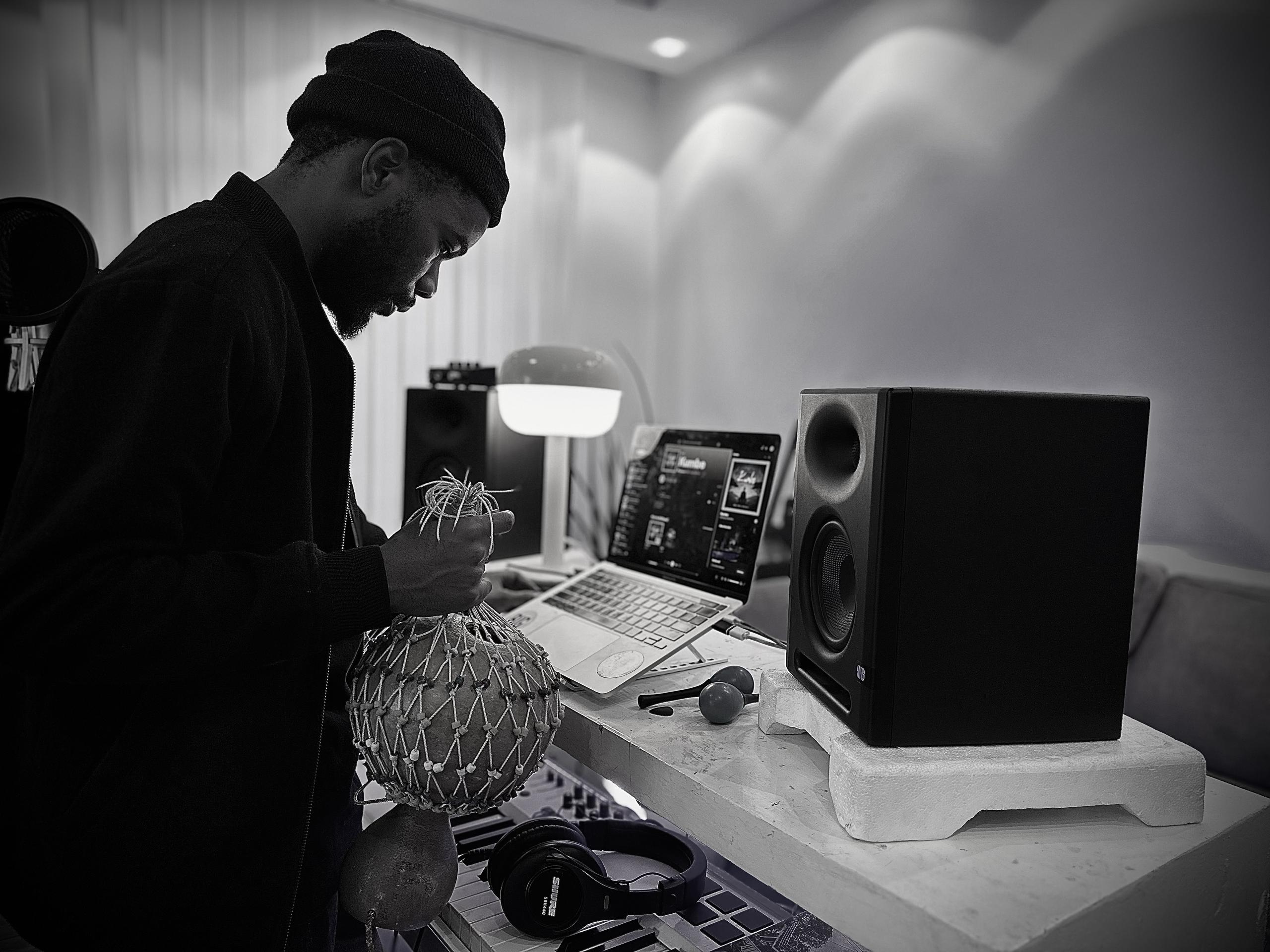 a picture of my in my studio holding a traditional instrument and looking at my computer